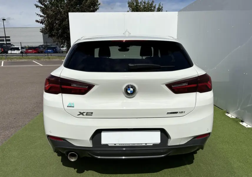 Vue arrière d'une BMW X2 blanche Alpine avec feux LED et sortie d'échappement chromée à gauche.