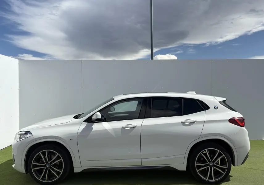 Profil côté gauche d'un BMW X2 blanc alpin avec jantes alliage 19 pouces et toit ouvrant panoramique en verre.