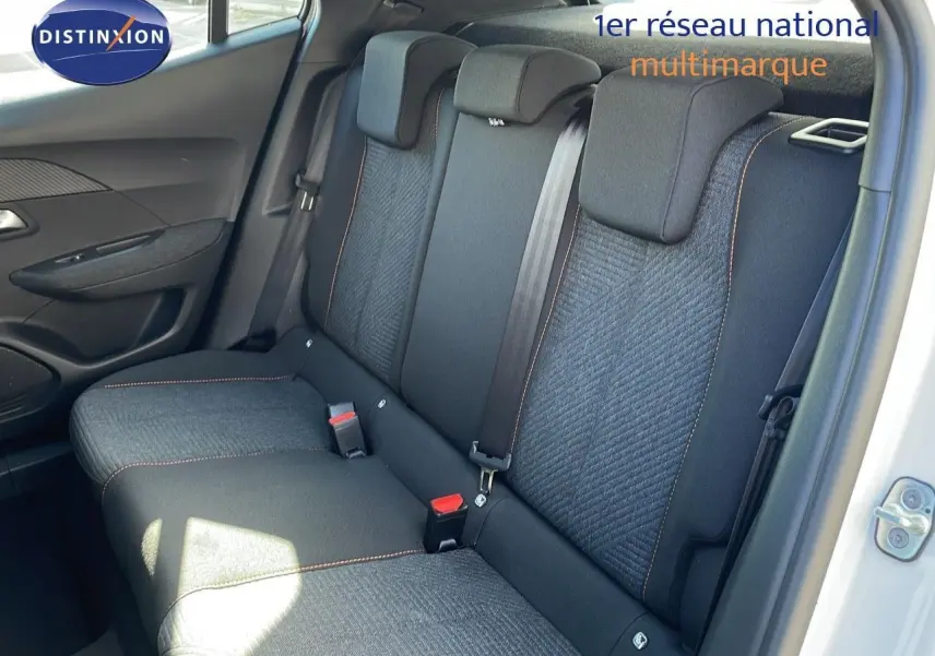 Vue intérieure arrière montrant les sièges arrière gris foncé avec surpiqûres orange d'une Peugeot 2008 blanche.