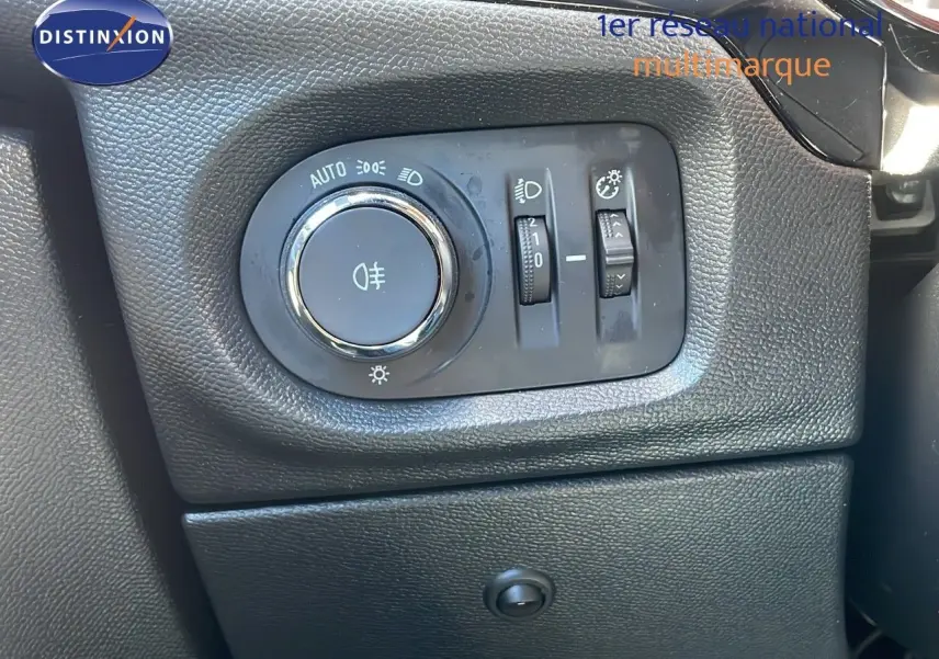 Gros plan sur la commande d'éclairage noire à gauche du tableau de bord d'une Opel Corsa blanc glacier 2022.