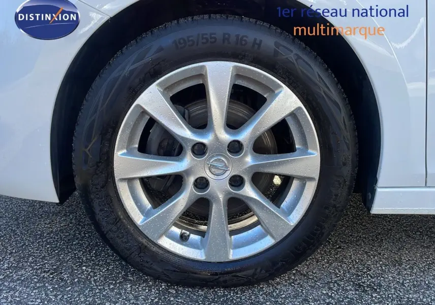 Gros plan sur la roue avant gauche d'une Opel Corsa blanc glacier avec jante alliage 16 pouces.