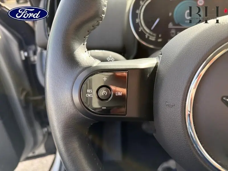 Gros plan sur la commande de régulateur de vitesse au volant cuir noir d'une MINI Countryman Melting Silver III 2023.