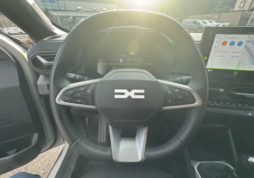Vue intérieure centrée sur le volant cuir du Dacia Duster TCE 130 4x2 Journey avec écran tactile et levier de vitesses.
