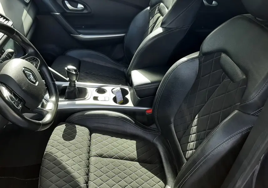 Vue intérieure côté conducteur du Renault Kadjar 2021, sièges noirs en cuir et tissu avec surpiqûres losanges.