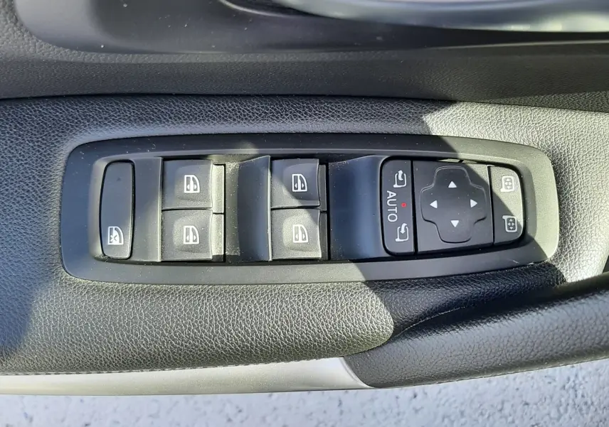Gros plan sur les commandes des vitres électriques et rétroviseurs sur la porte côté gauche d’un Renault Kadjar gris titanium.