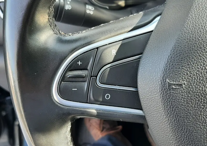 Gros plan sur les commandes de régulateur de vitesse au volant cuir noir du Renault Kadjar 1.5 Blue dCi 115ch Intens.