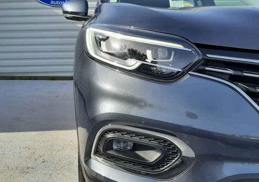 Gros plan sur l'avant gauche du Renault Kadjar gris titanium 2021, mettant en valeur le phare LED et la calandre.
