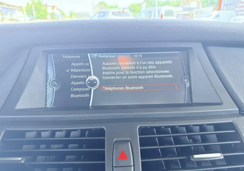 Vue intérieure centrée sur l'écran multimédia du tableau de bord du BMW X6 noir, affichant le menu Bluetooth.