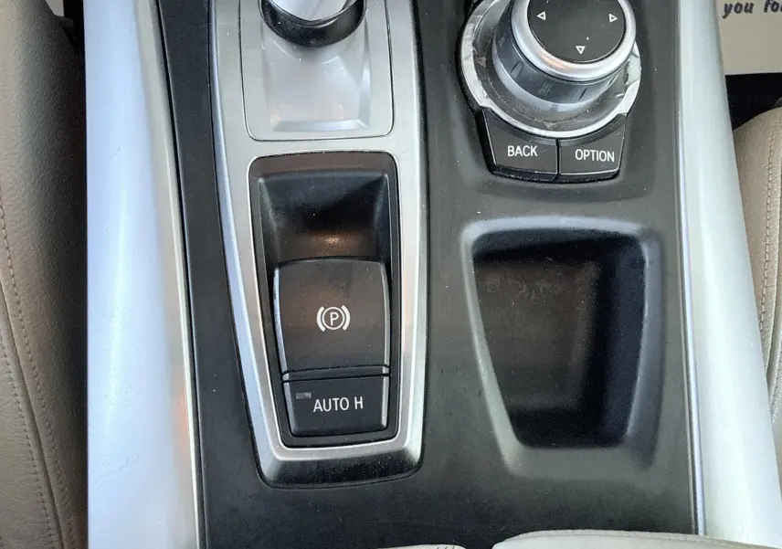Vue rapprochée de la console centrale grise et noire du BMW X6 noire, avec commandes électroniques et molette de navigation.