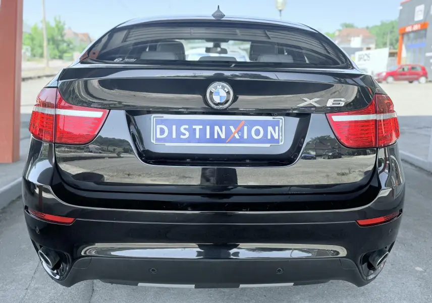 Vue arrière d’un BMW X6 noir avec feux rouges allongés et double sortie d’échappement chromée.