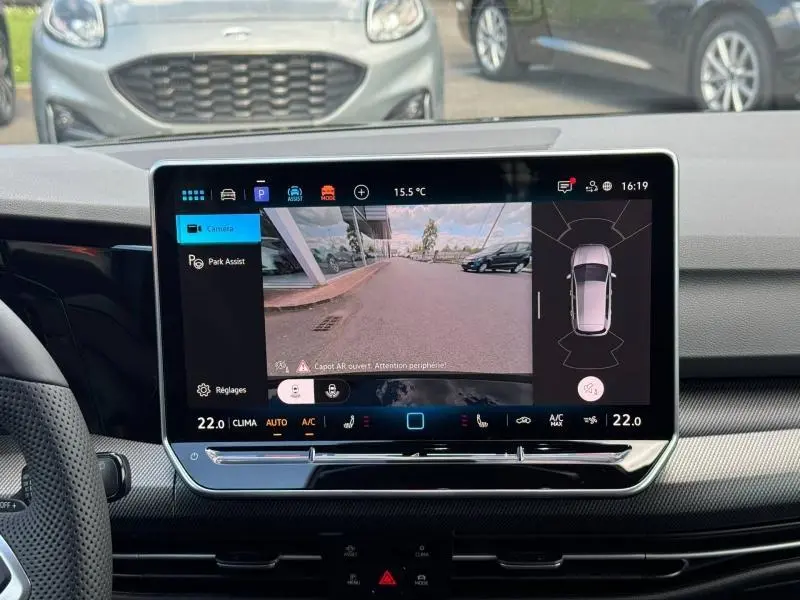 Écran tactile intérieur montrant la caméra de recul d'une Volkswagen Golf noire, vue depuis le poste de conduite.