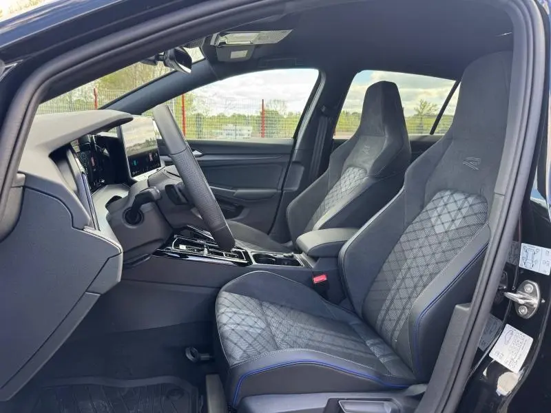 Vue intérieure côté conducteur de la Volkswagen Golf R-Line 2026 avec sièges sport gris anthracite et surpiqûres bleues.