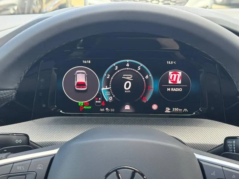 Vue intérieure du tableau de bord numérique de la Volkswagen Golf noir Grenadilla, affichant la vitesse et la radio M Radio.