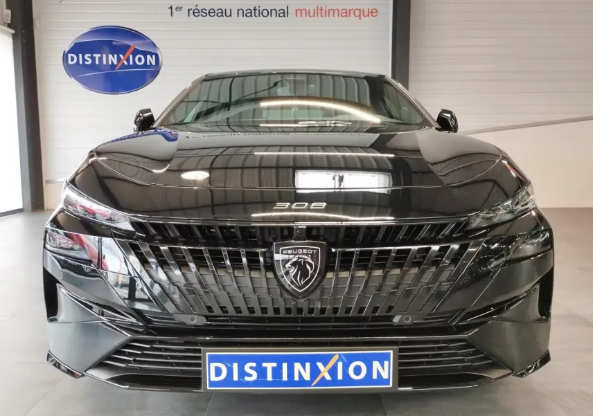 Vue frontale d'une Peugeot 308 noire métallisée avec calandre et blason Peugeot distinctifs, en intérieur showroom.