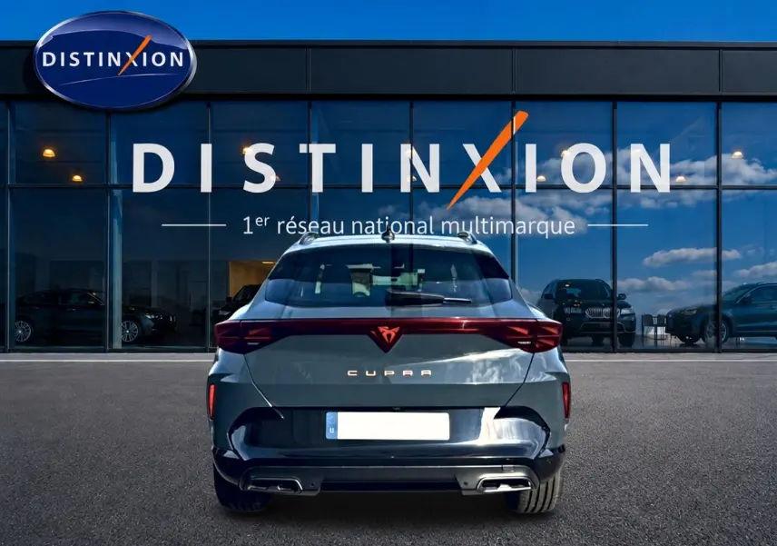 Vue arrière d'une CUPRA Formentor bleu fjord 2026 avec feux LED et double sortie d'échappement, devant un showroom Distinxion.