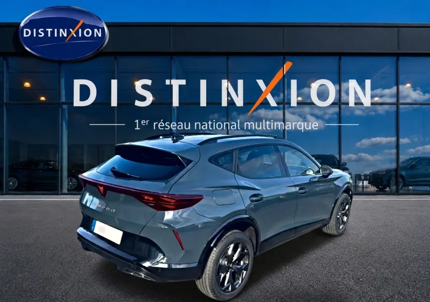 Vue 3/4 arrière droite d'un CUPRA Formentor 1.5 eTSI hybrid bleu fjord avec jantes noires devant une vitrine Distinxion.