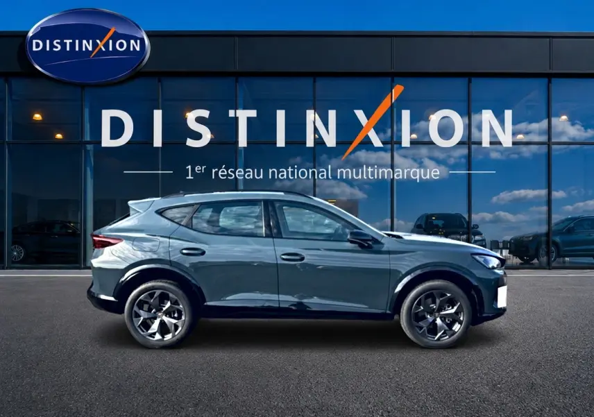 Vue de profil côté gauche du CUPRA Formentor 1.5 etsi hybrid 150 DSG7 en bleu fjord devant une vitrine Distinxion.