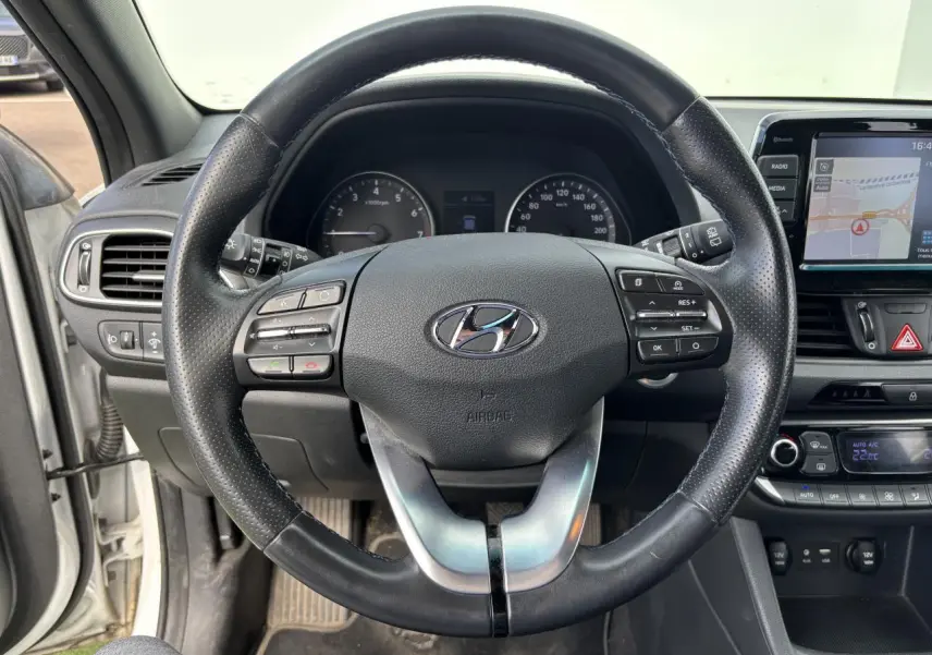 Volant cuir noir avec commandes intégrées et tableau de bord de la Hyundai i30 III SW blanc vue côté conducteur intérieur