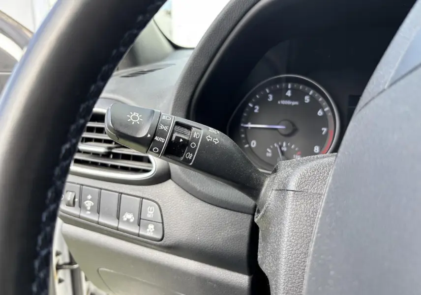 Gros plan sur la manette des feux et clignotants à gauche du volant d'une Hyundai i30 blanche de 2018.