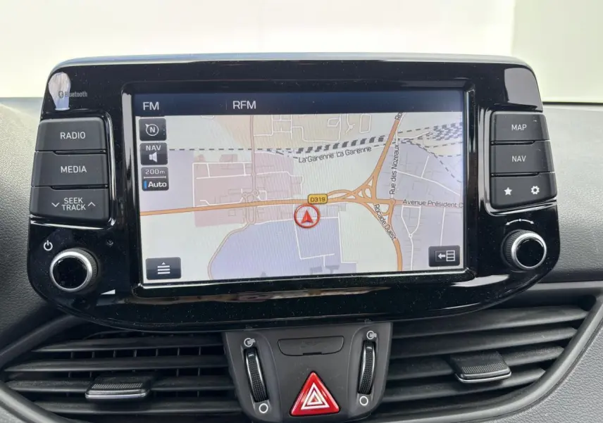 Écran tactile central du système de navigation de la Hyundai i30 III SW Edition Navi, avec commandes autour et tableau de bord noir.