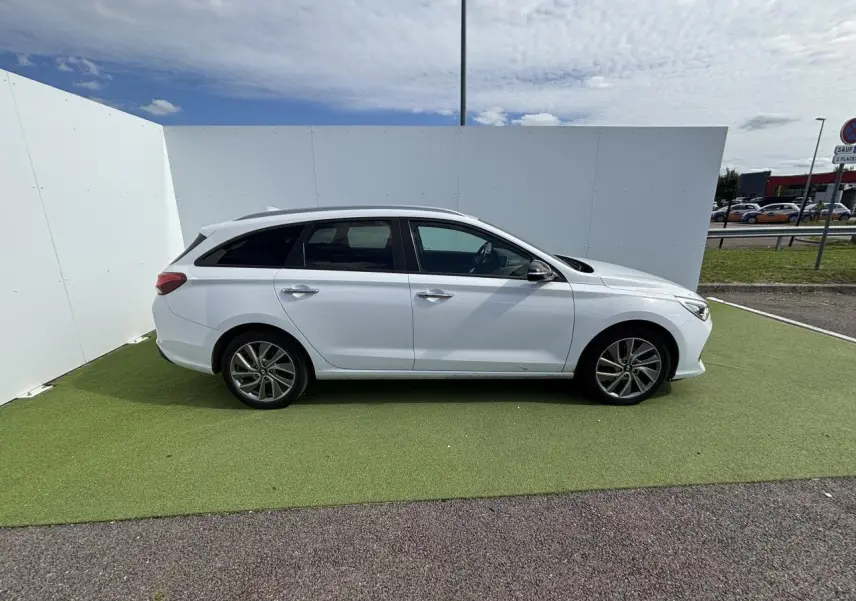 Profil droit d'une Hyundai i30 SW blanche 2018 sur fond clair, avec jantes alliage 17 pouces et vitres surteintées.