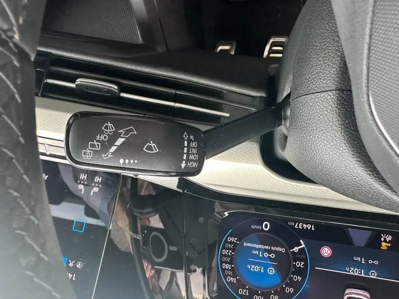 Vue rapprochée du commodo d’essuie-glace noir dans l’habitacle d’une Volkswagen Golf 2024 noir intense nacrée.