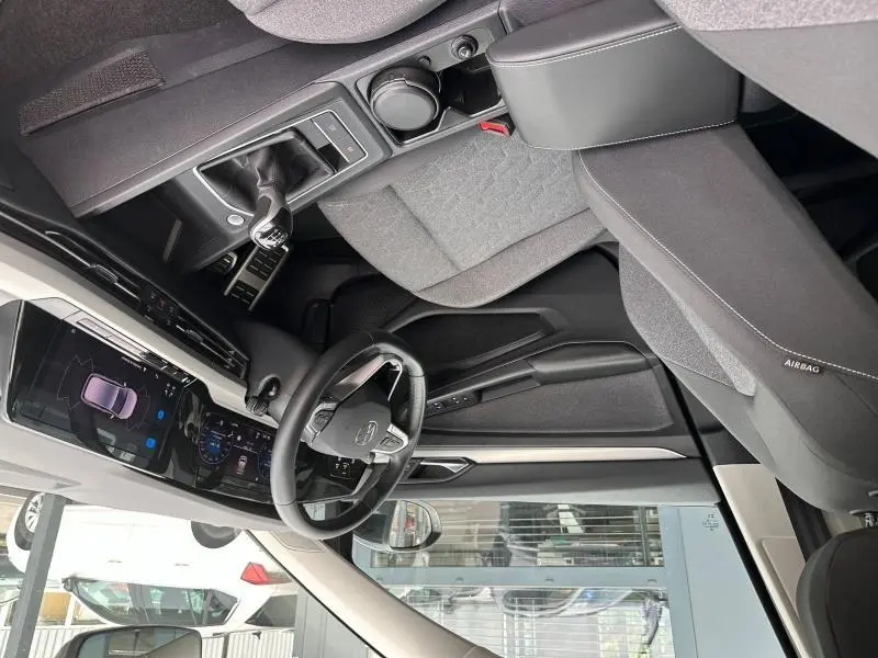 Vue intérieure côté conducteur de la Volkswagen Golf 1.5 eTSI 2024, avec volant cuir multifonction et accoudoir central noir.