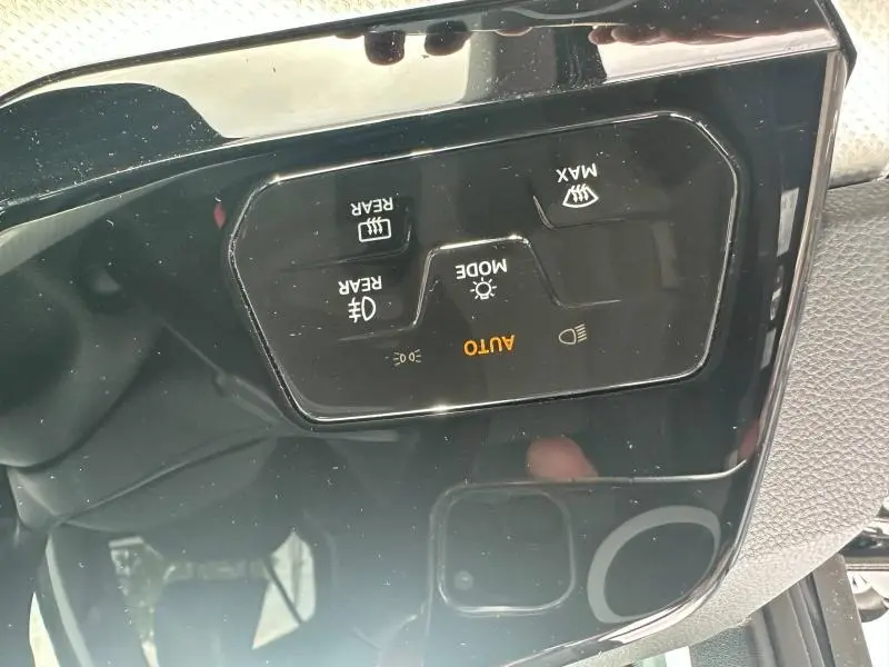 Gros plan sur les commandes d’éclairage et chauffage de siège en noir brillant dans une Volkswagen Golf 2024 noir nacré.