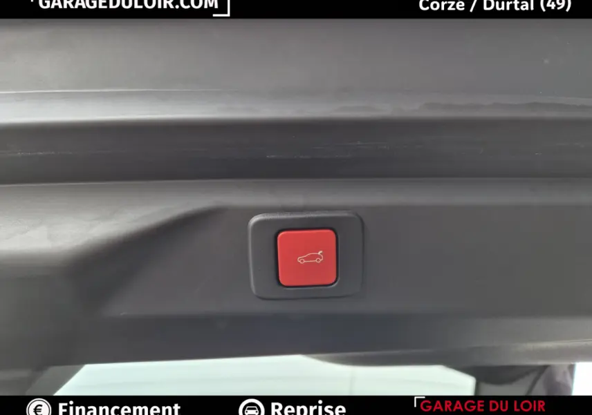Bouton rouge d'ouverture électrique du coffre sur la partie intérieure du hayon d'un Peugeot 3008 blanc.
