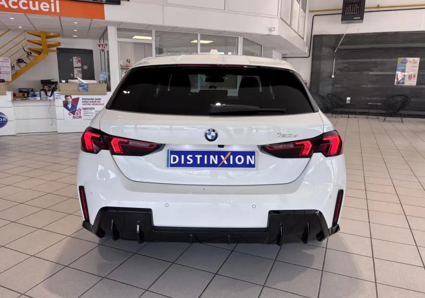 Vue arrière d'une BMW Série 1 120d M Sport blanche de 2025 avec feux LED et diffuseur noir en concession.