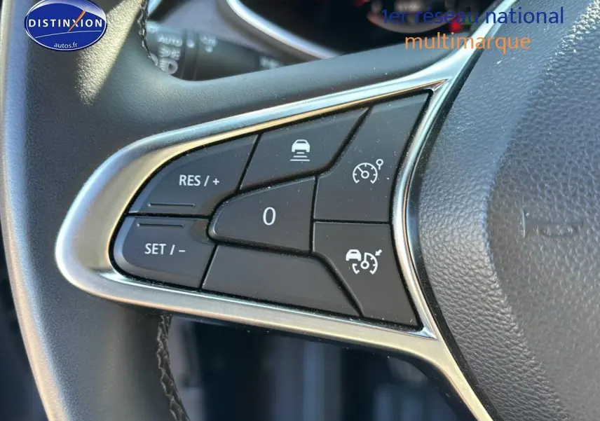 Gros plan sur les commandes de régulateur de vitesse au volant textile enduit gris de la Renault Clio V 2024.