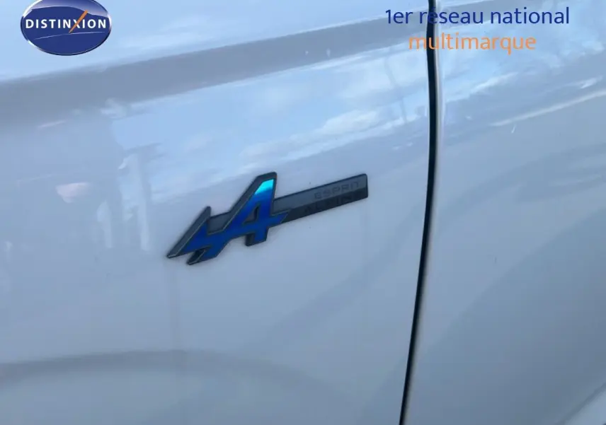 Gros plan sur l'écusson Esprit Alpine bleu sur la portière blanche du Renault Austral Iconic 2024 hybride.