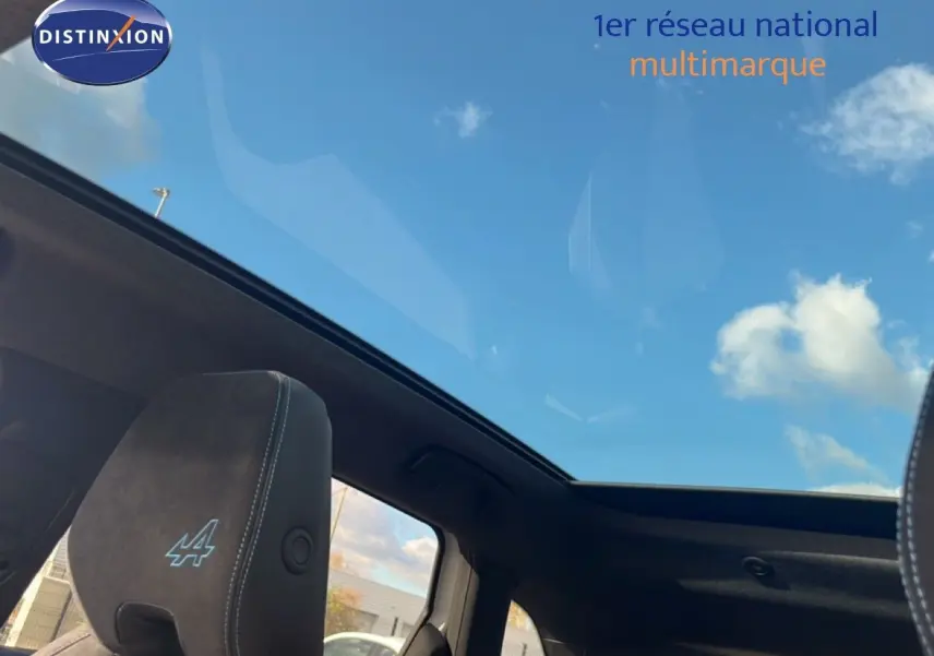 Toit panoramique ouvert vu de l'intérieur sur les sièges noirs avec logo Alpine du Renault Austral Iconic Esprit Alpine.