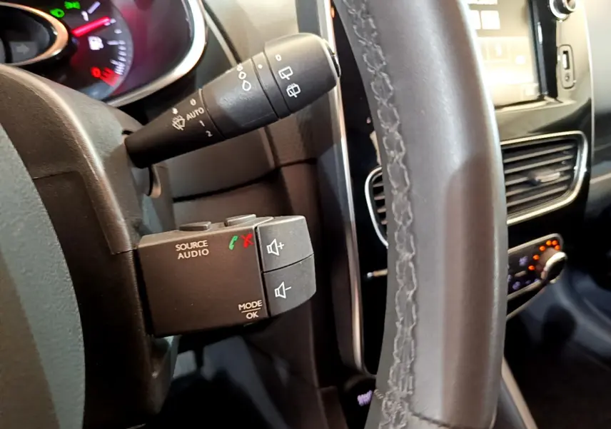 Gros plan sur le volant cuir et commandes audio au volant de la Renault Clio Business TCe 90 blanche de 2019.