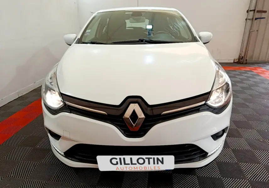 Vue frontale d'une Renault Clio Business TCe 90 blanche avec phares allumés et logo Renault bien visible.