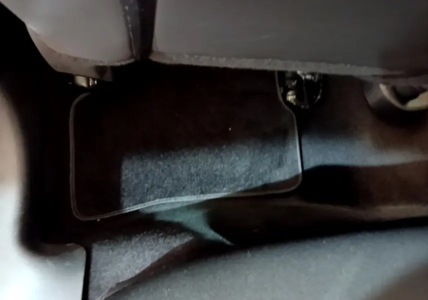 Gros plan sur le tapis de sol noir sous le siège avant d'une Renault Clio Business TCe 90 blanche de 2019.