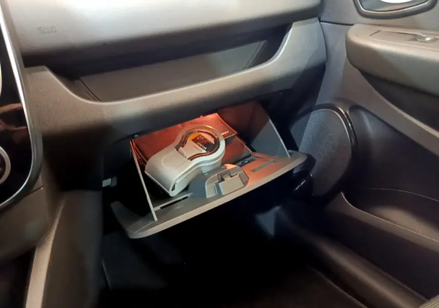 Vue rapprochée de la boîte à gants ouverte côté passager d'une Renault Clio Business blanche avec objets à l'intérieur.