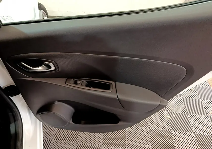 Vue rapprochée de la porte côté gauche d'une Renault Clio Business blanche, montrant la poignée et les commandes de fenêtre.