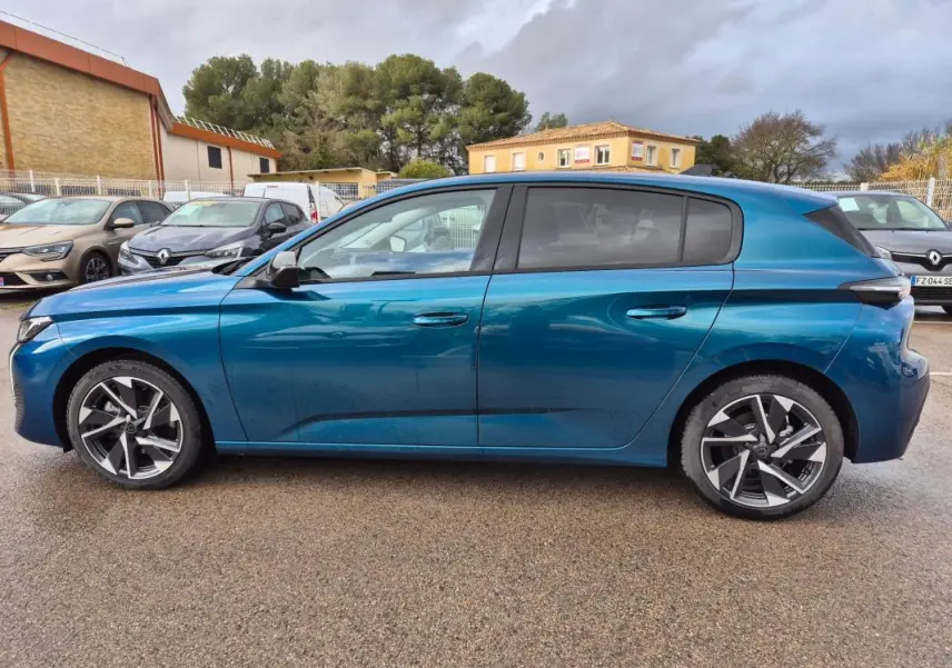 Vue latérale droite d'une Peugeot 308 bleu métallisé 2024 avec jantes alliage 17 pouces et vitres teintées.