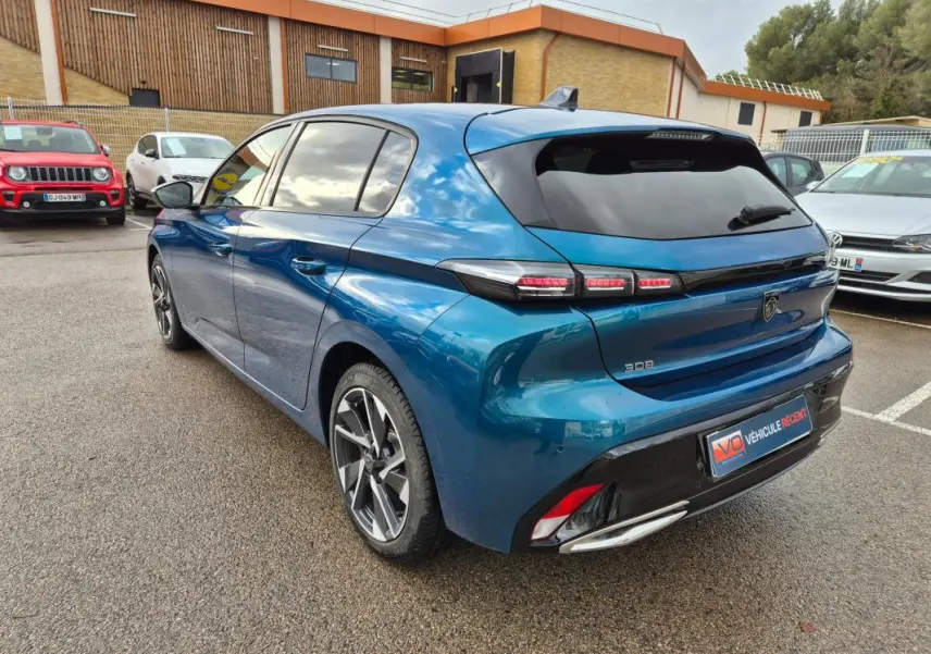 Vue 3/4 arrière droite d'une Peugeot 308 bleu 2024 avec jantes alliage et feux arrière LED distinctifs.