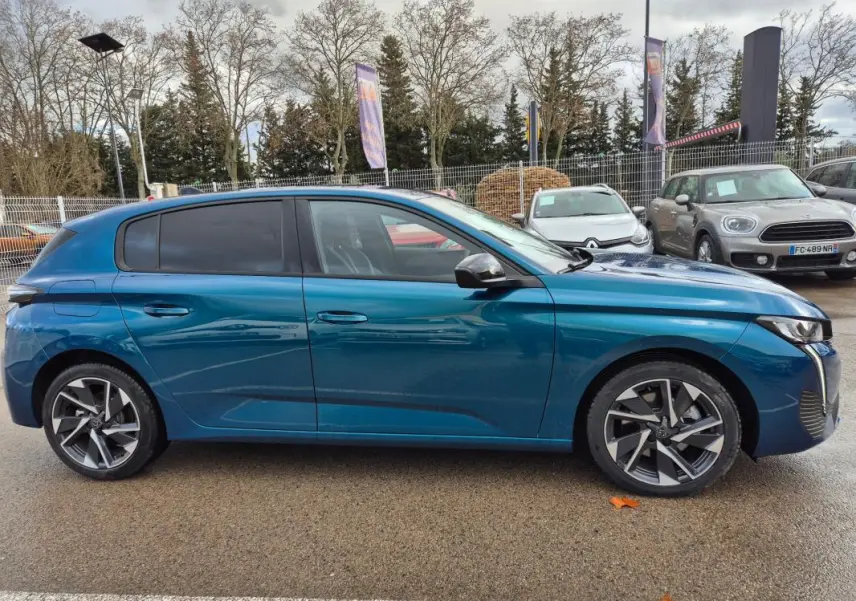 Profil côté gauche d'une Peugeot 308 bleu 2024 avec jantes alliage 17 pouces et vitres teintées.