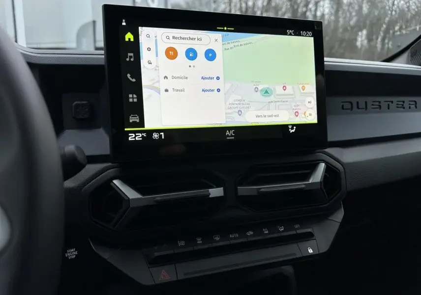 Vue intérieure du tableau de bord du Dacia Duster 2025 avec écran tactile central affichant la navigation.