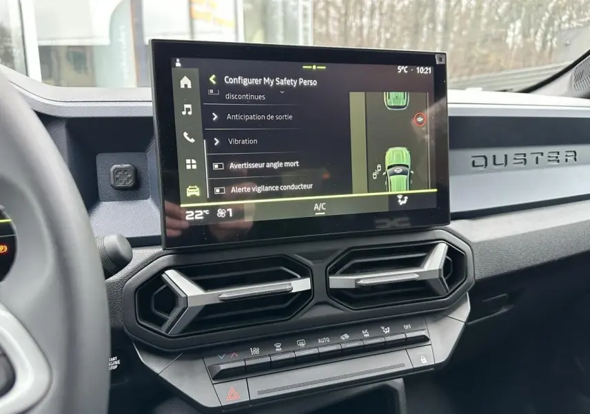 Vue intérieure du tableau de bord du Dacia Duster 2025 noir, avec écran tactile central et aérateurs hexagonaux.