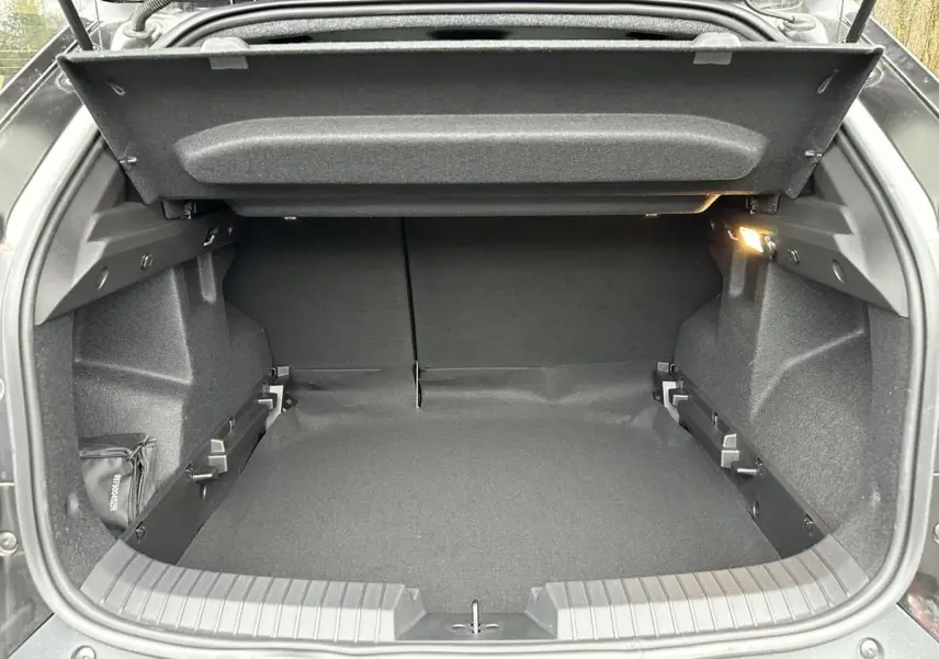 Coffre ouvert du Dacia Duster noir 2025, vue arrière, montrant l’espace de chargement et l’éclairage intérieur.