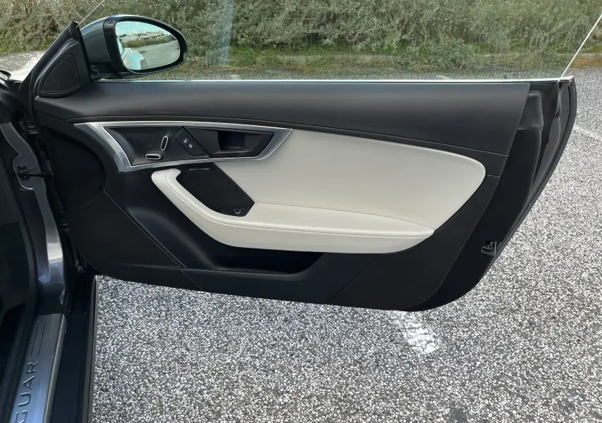 Vue côté gauche de la porte intérieure ouverte d’une Jaguar F-TYPE gris Corris avec garniture cuir noir et beige et inserts aluminium.