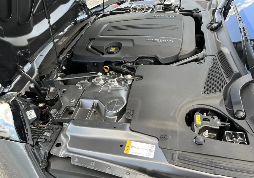 Vue rapprochée du compartiment moteur d'une Jaguar F-TYPE 2018 gris Corris avec capot ouvert, mettant en valeur le moteur Ingenium.
