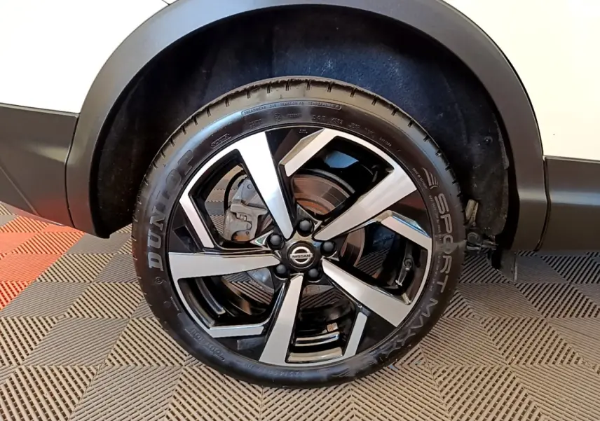 Gros plan sur la roue avant droite du Nissan Qashqai blanc avec jante alliage noire et argentée.