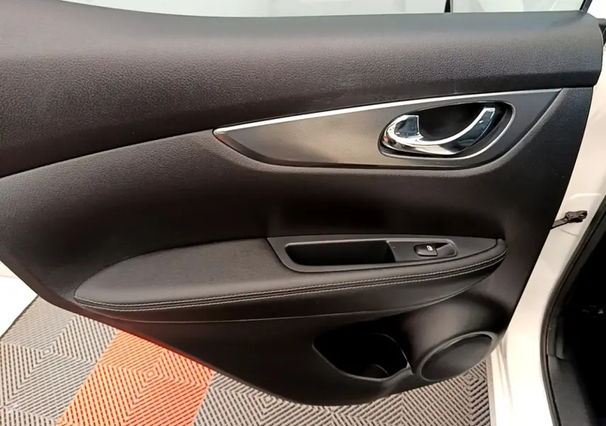 Gros plan sur la porte avant droite noire du Nissan Qashqai blanc, avec poignée chromée et commande de vitre.