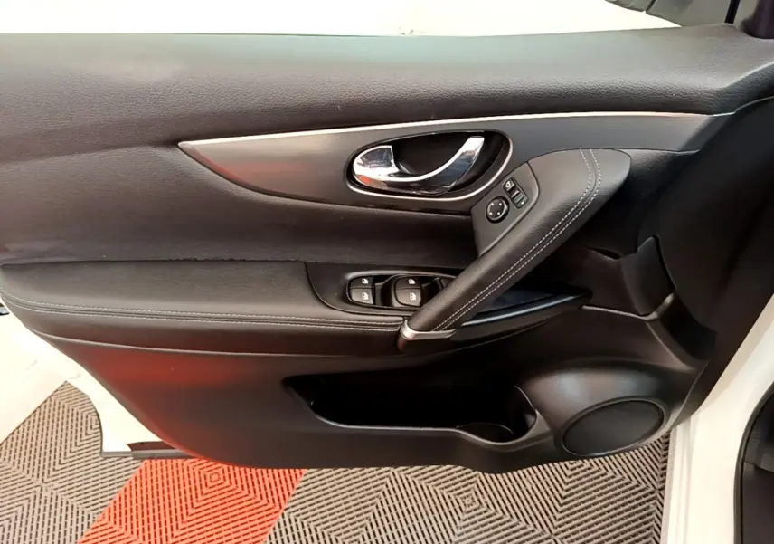 Vue intérieure côté gauche de la porte avant noire du Nissan Qashqai blanc avec commandes de vitres et poignée chromée.