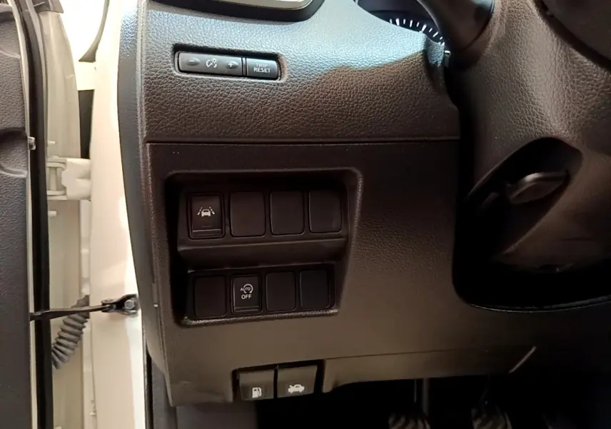 Vue rapprochée côté gauche du tableau de bord noir du Nissan Qashqai blanc avec commandes d’aide à la conduite.
